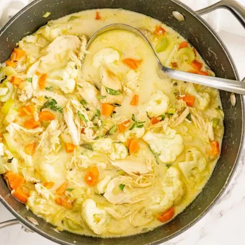 Chicken cauliflower soup with carrots and green garnish.