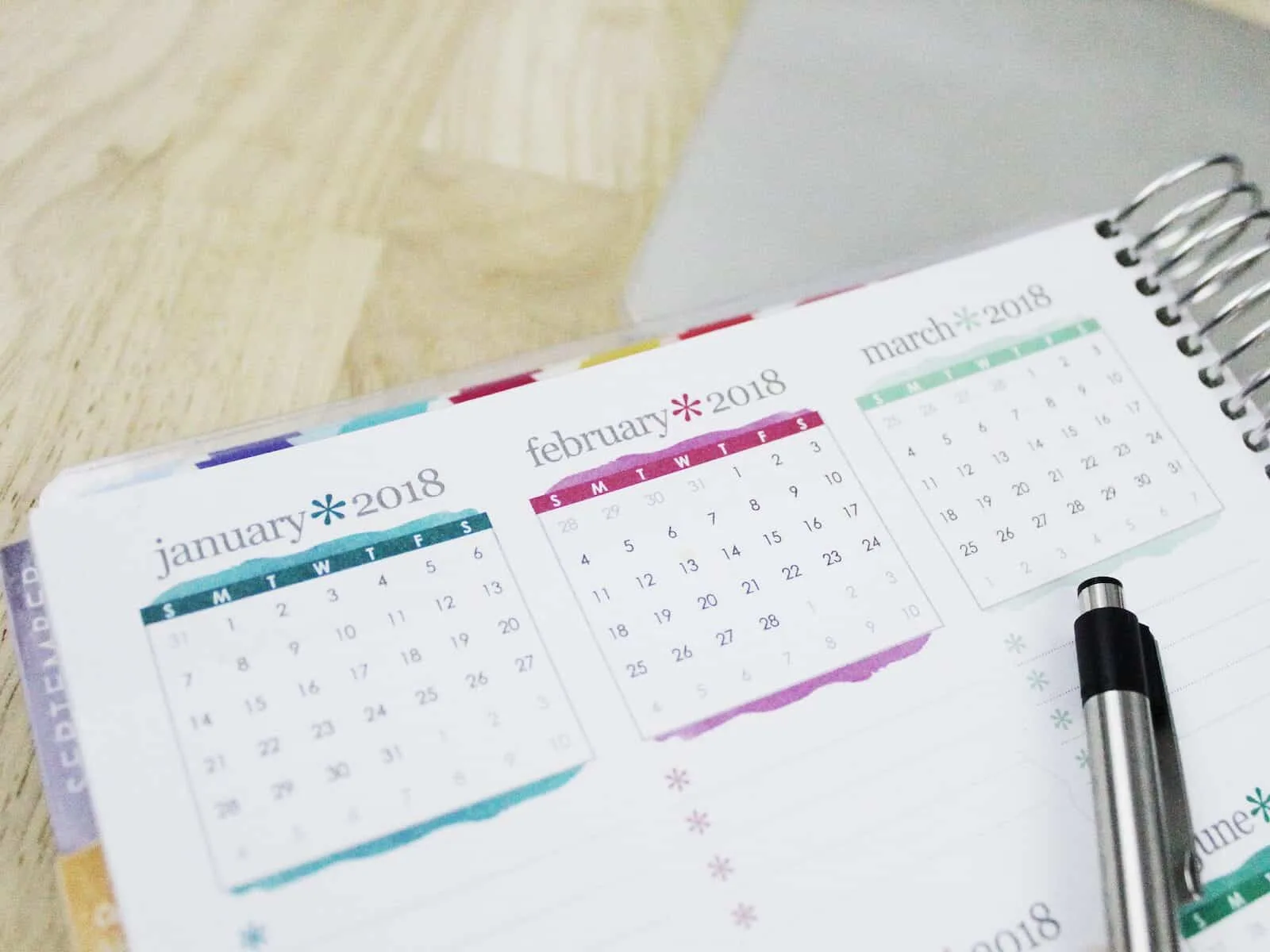 Calendar and pen on wooden table.