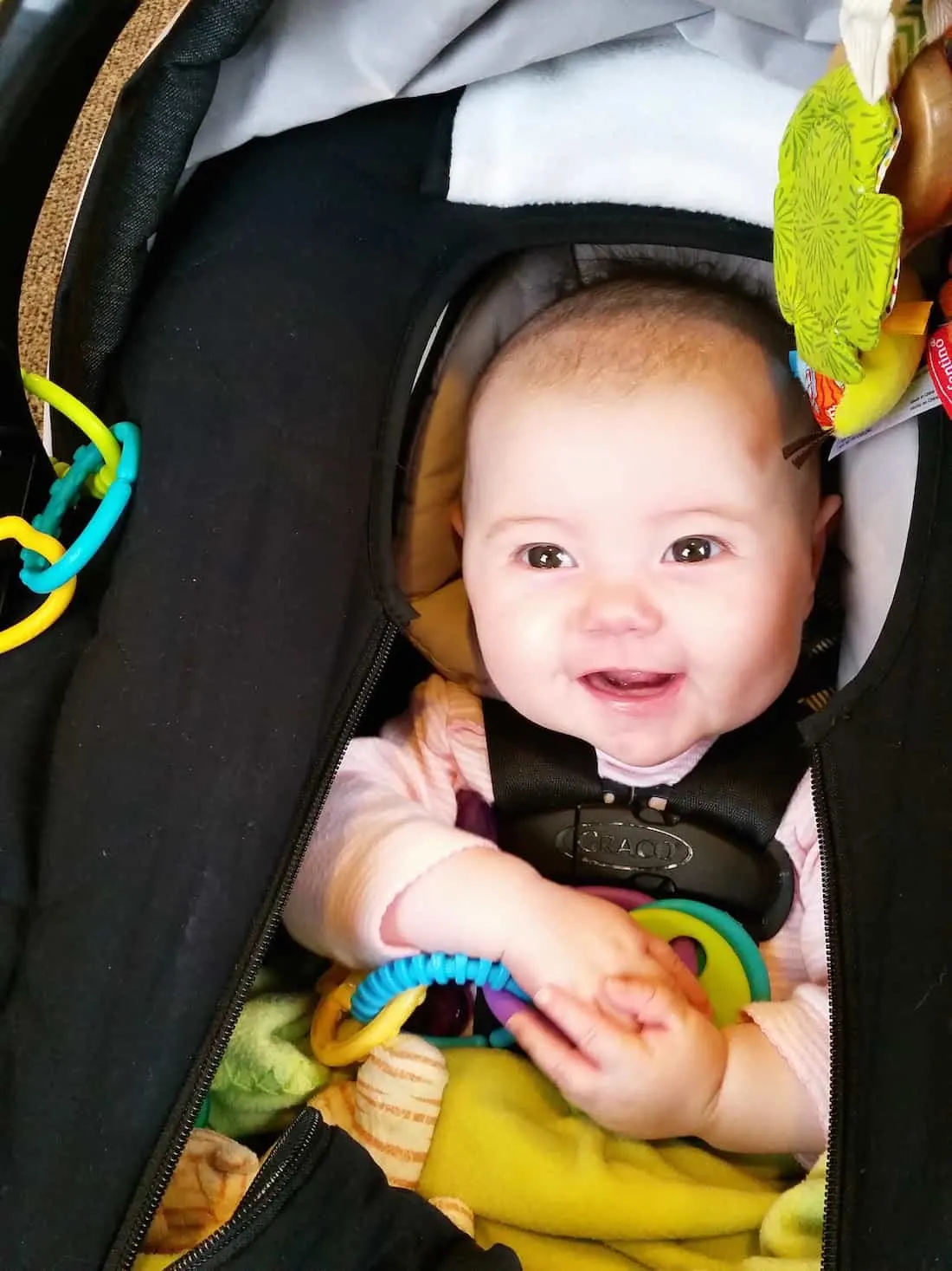 Baby plays with toys in car seat.