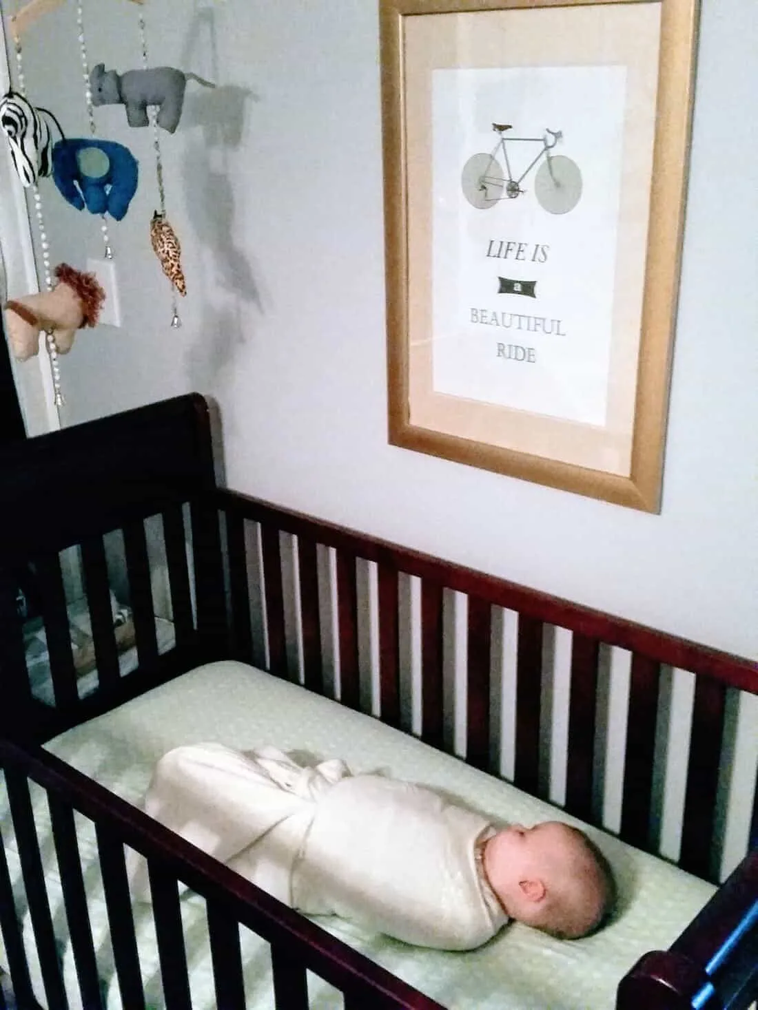 Baby girl sleeps in crib with swaddle.