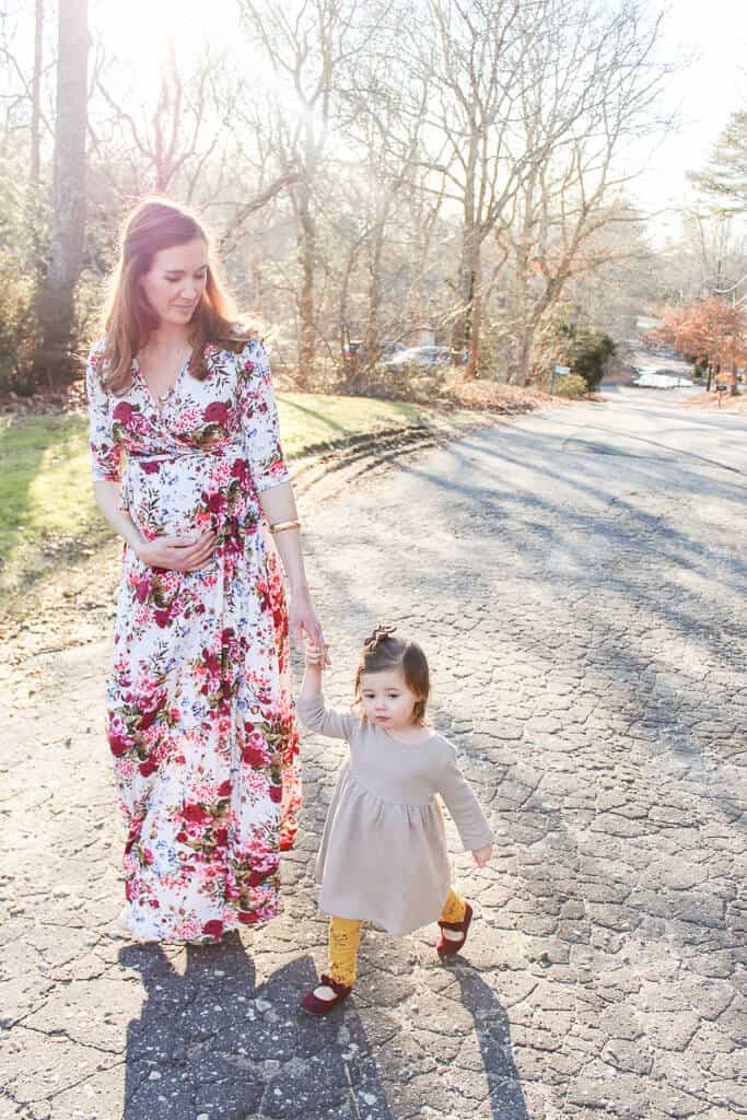 Pregnant woman walks down street with daughter.