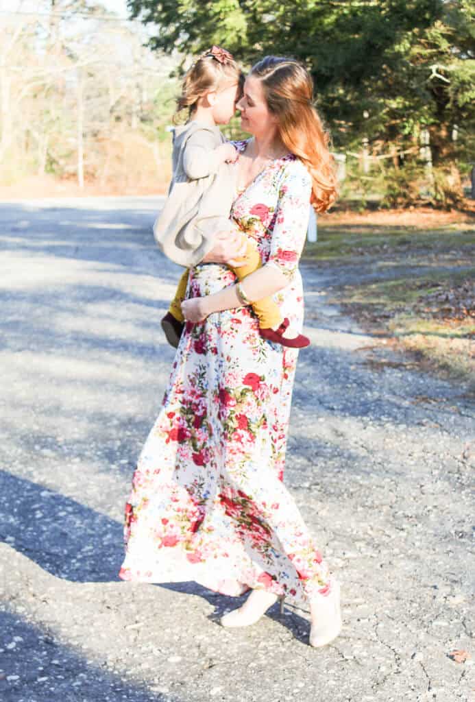 Pregnant woman holds daughter for pictures.