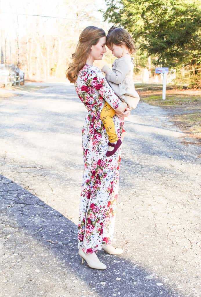 Woman holds daughter for pictures during second pregnancy.