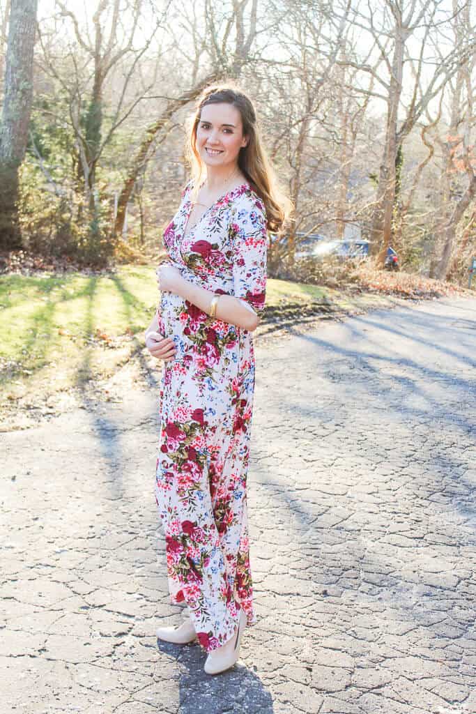 Pregnant woman in floral dress poses for pictures.