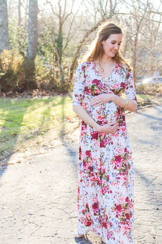 Pregnant woman poses for pictures in floral maxi dress.