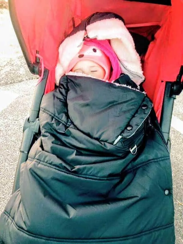 Toddler girl sleeps in warm and cozy stroller.
