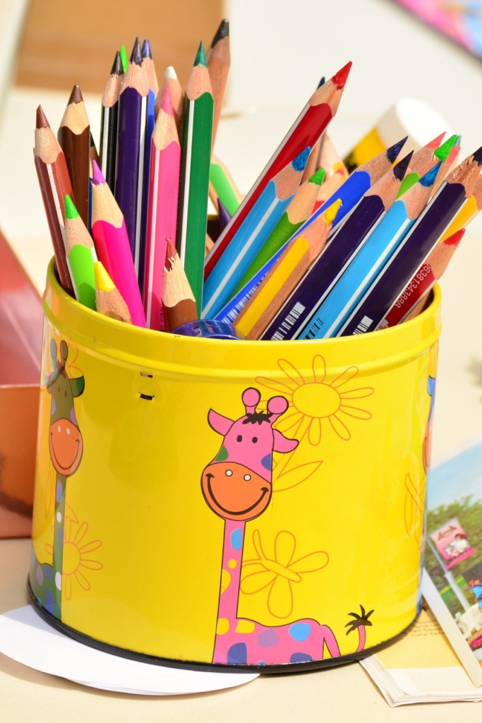 Colored pencils in a yellow container with a pink giraffe on it.
