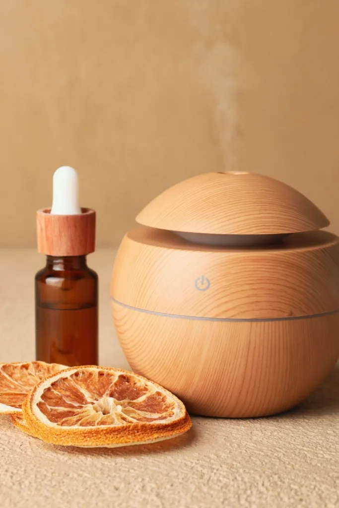 An aroma diffuser next to a bottle of essential oils and dried citrus slices.
