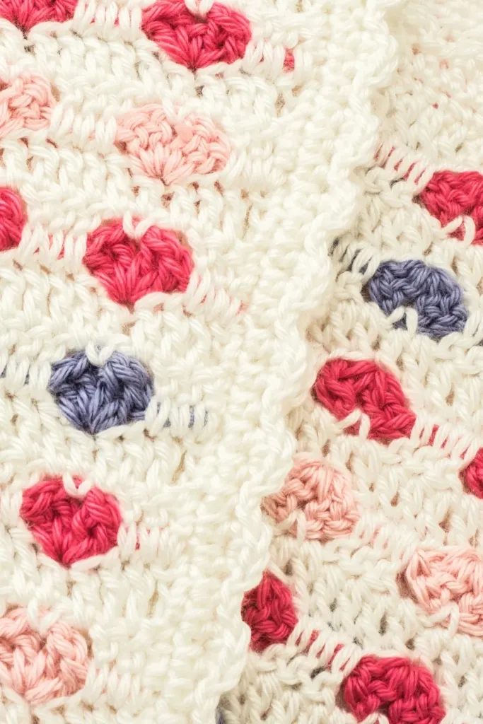A crocheted blanket with pink and blue hearts.