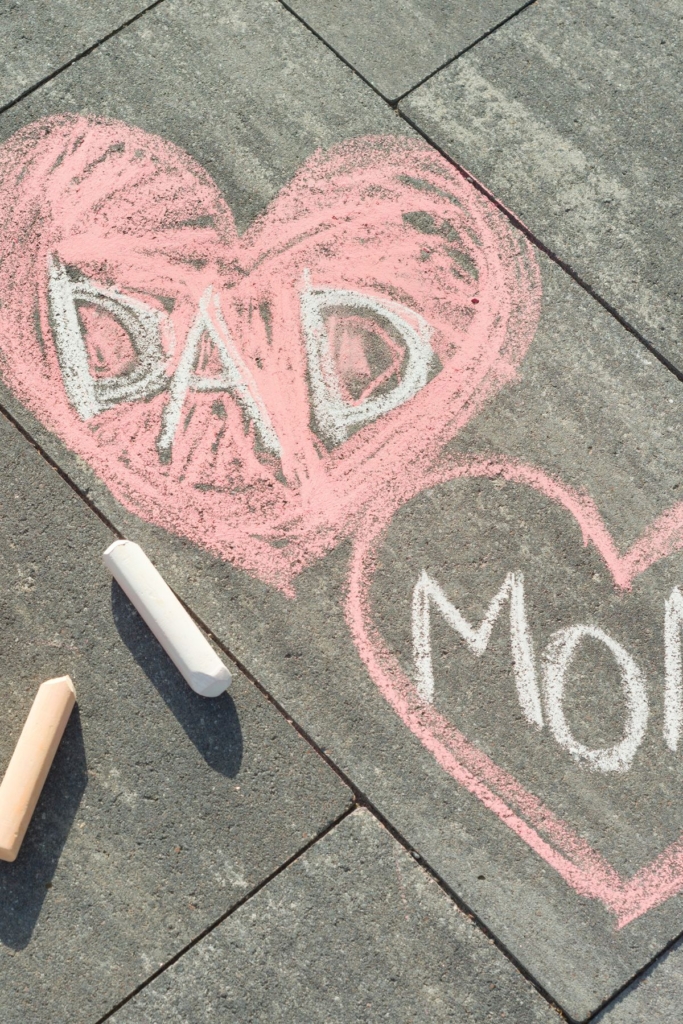 Mom and dad written inside hearts drawn with sidewalk chalk.