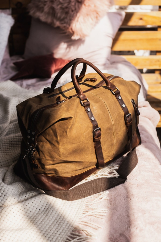 A men's travel duffle bag on a bed.