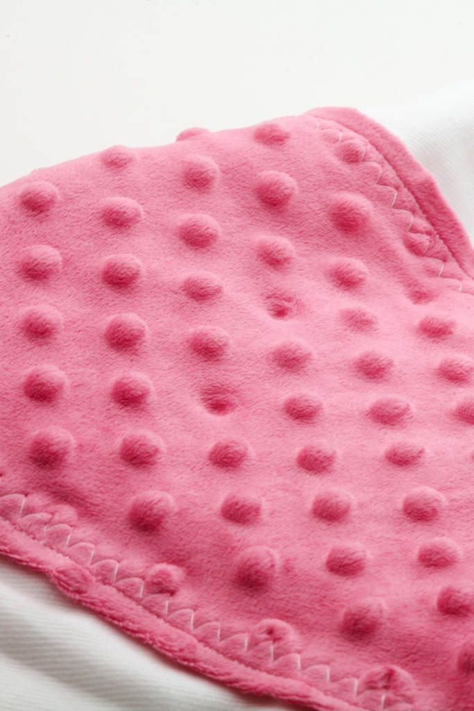 A pink puffy baby blanket on a white background.
