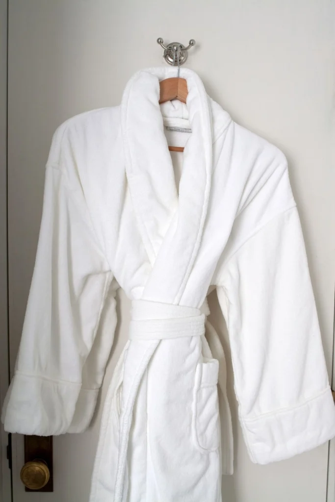 A plush white robe hangs from a wooden hanger.