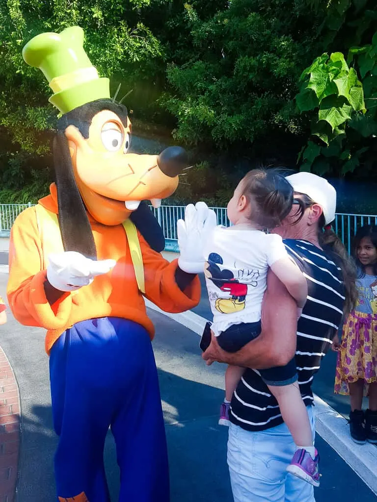 Mother introduces toddler girl to Goofy at Disney.