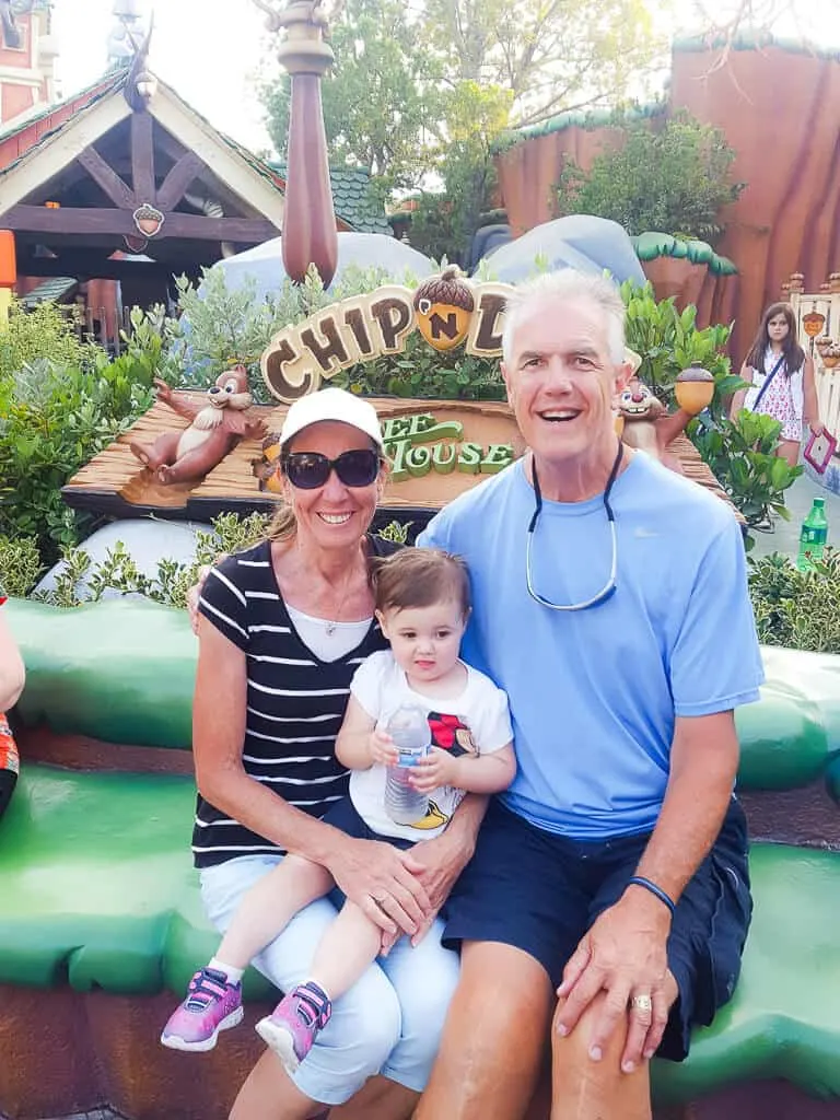 Grandparents pose with granddaughter at Disney Park.