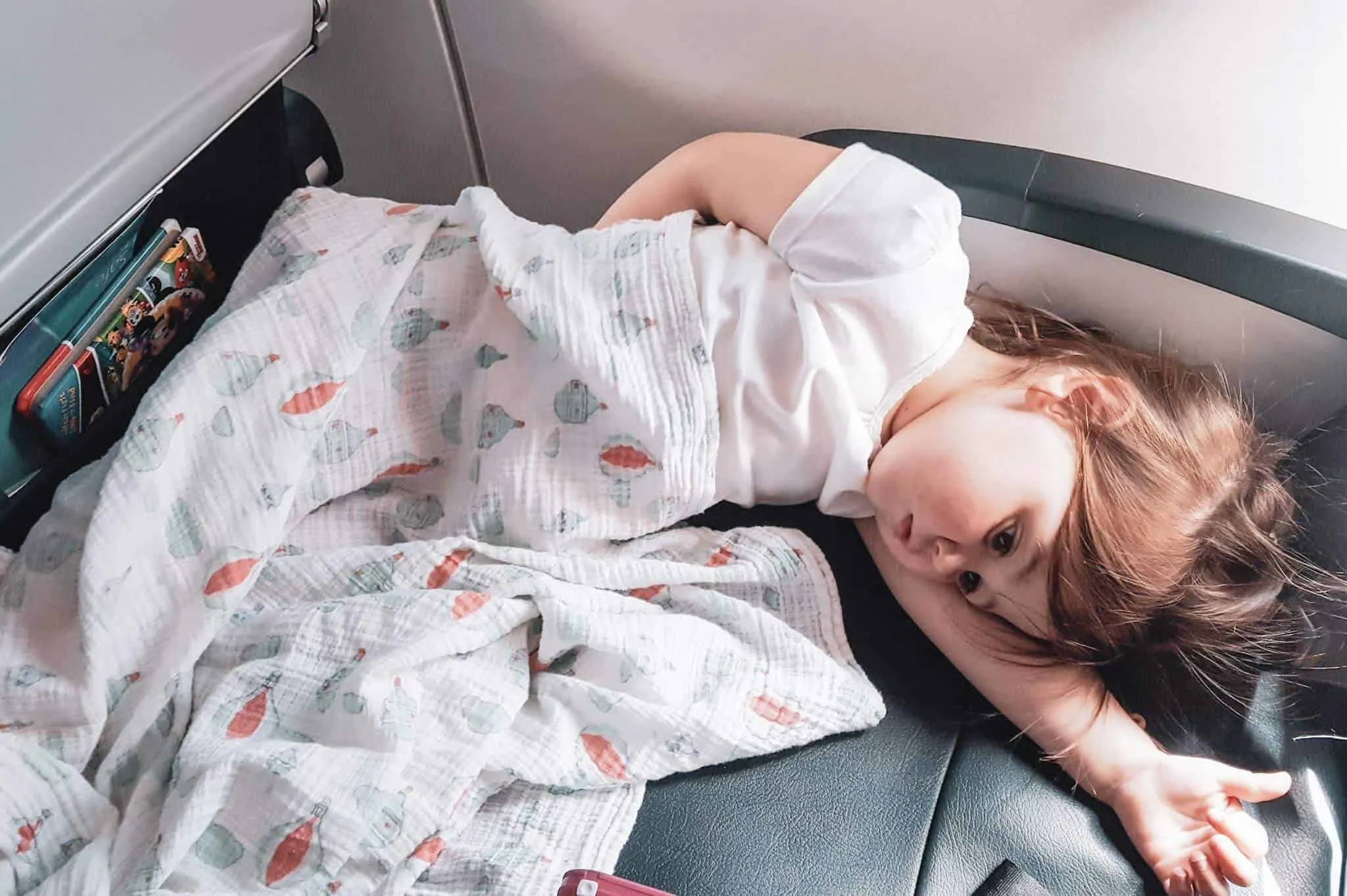 Toddler uses travel gear to sleep on plane.