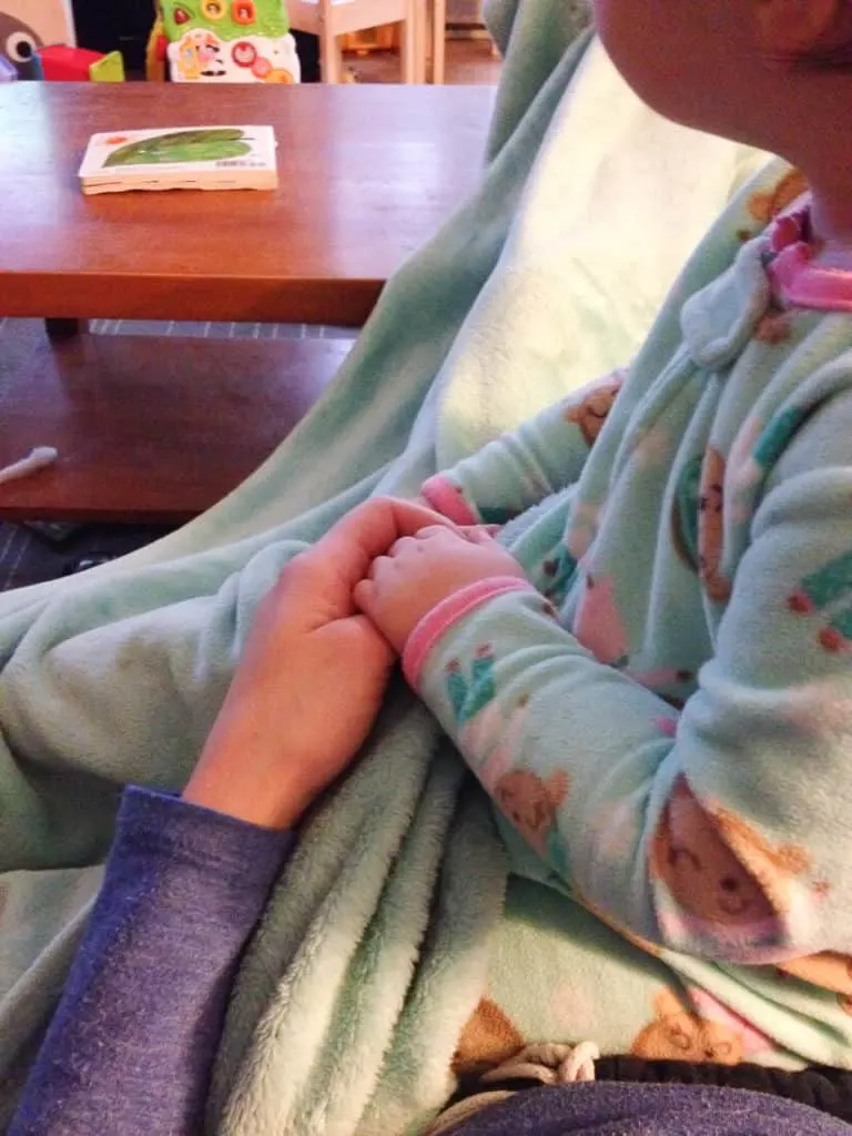 Woman holds baby girl\'s hand.