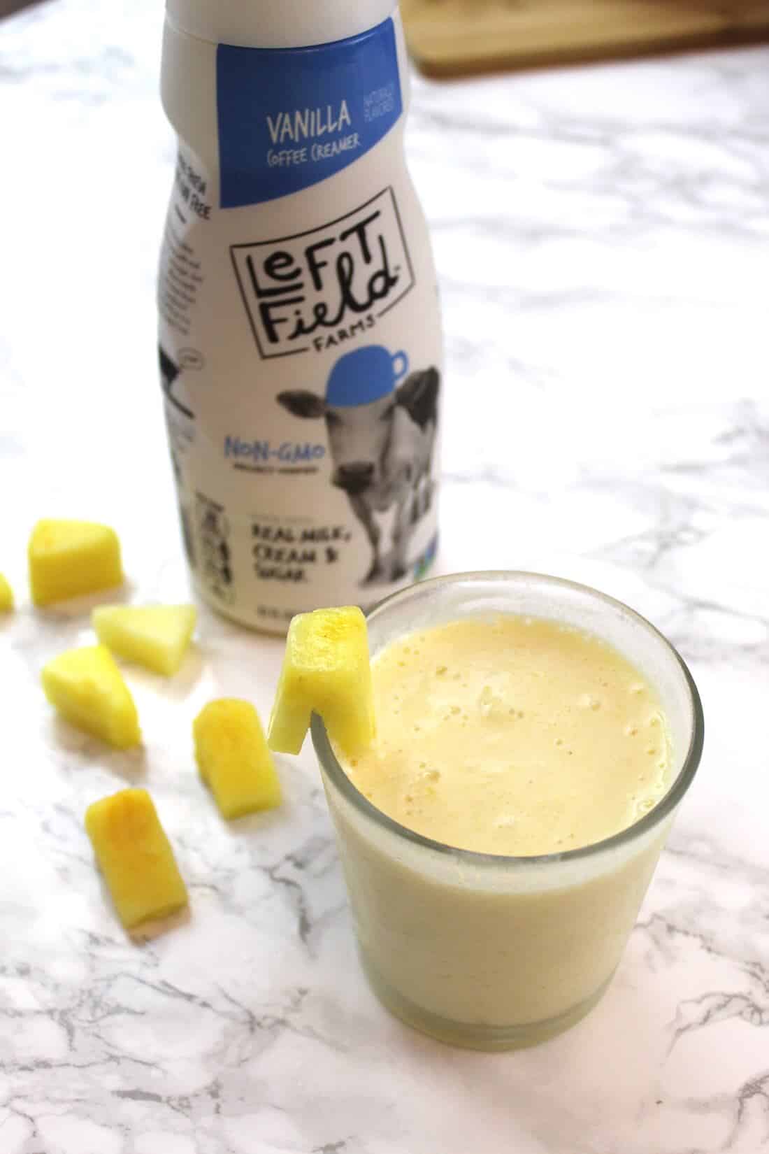 Pineapple smoothie in glass next to bottle of Left Field milk.