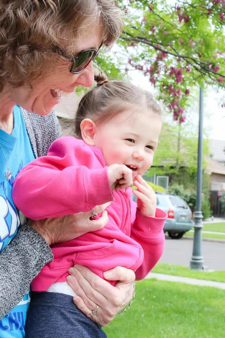 Woman holds baby girl outdoors.