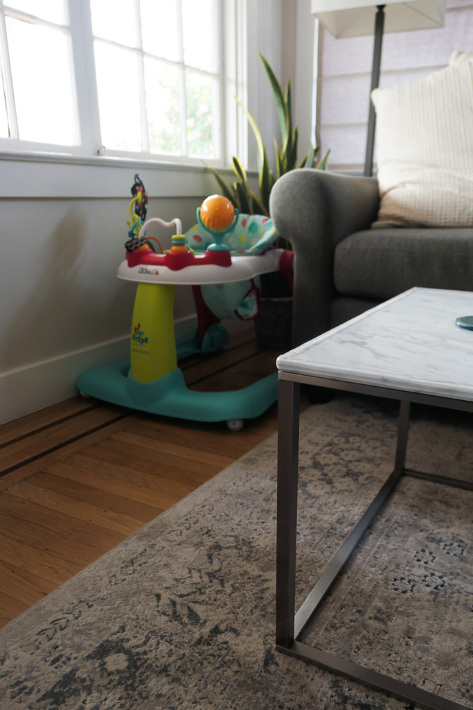A marble coffee table in a living room with a protective baby proofing band around the edge.