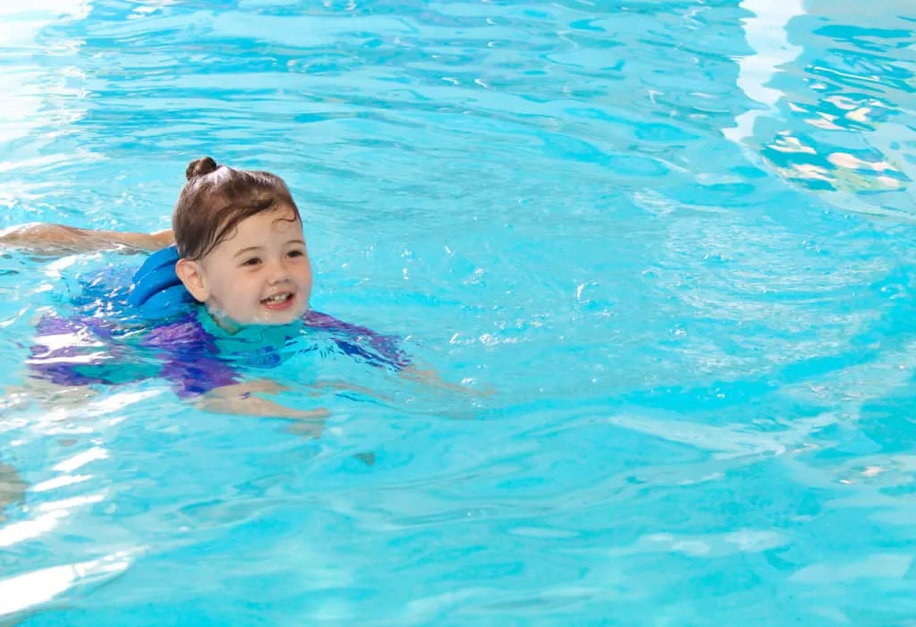 Toddler girl swims in pool.