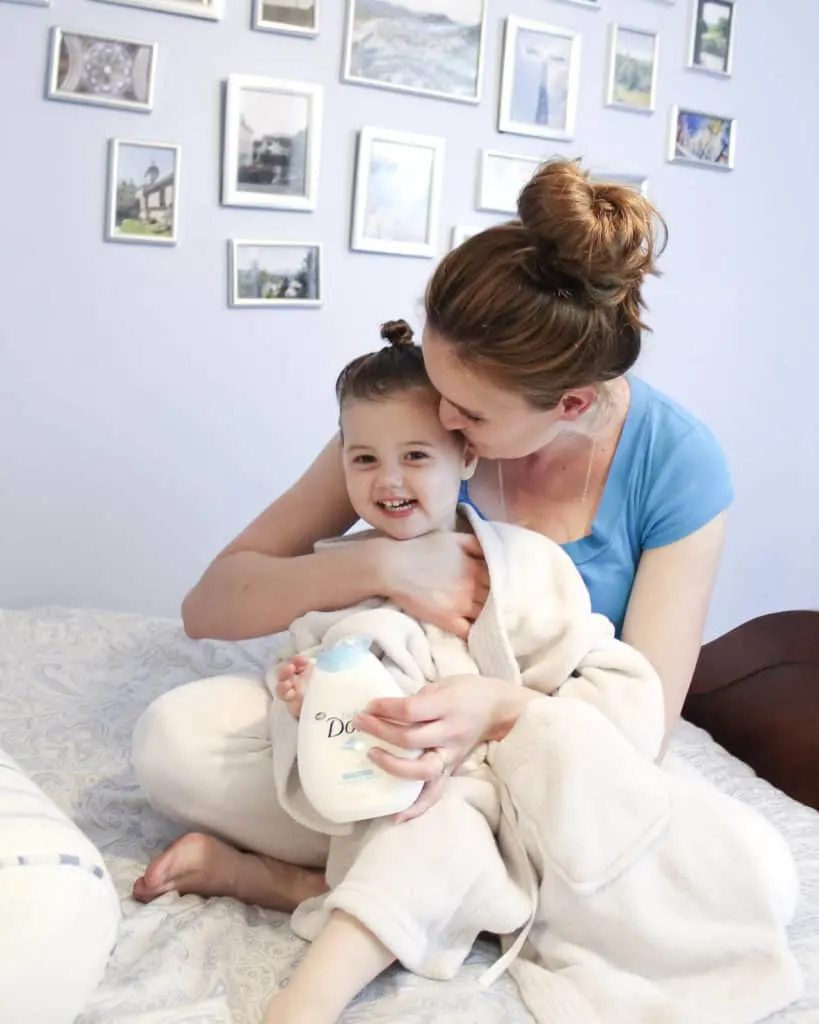 Mother and daughter sit on bed after bath time.