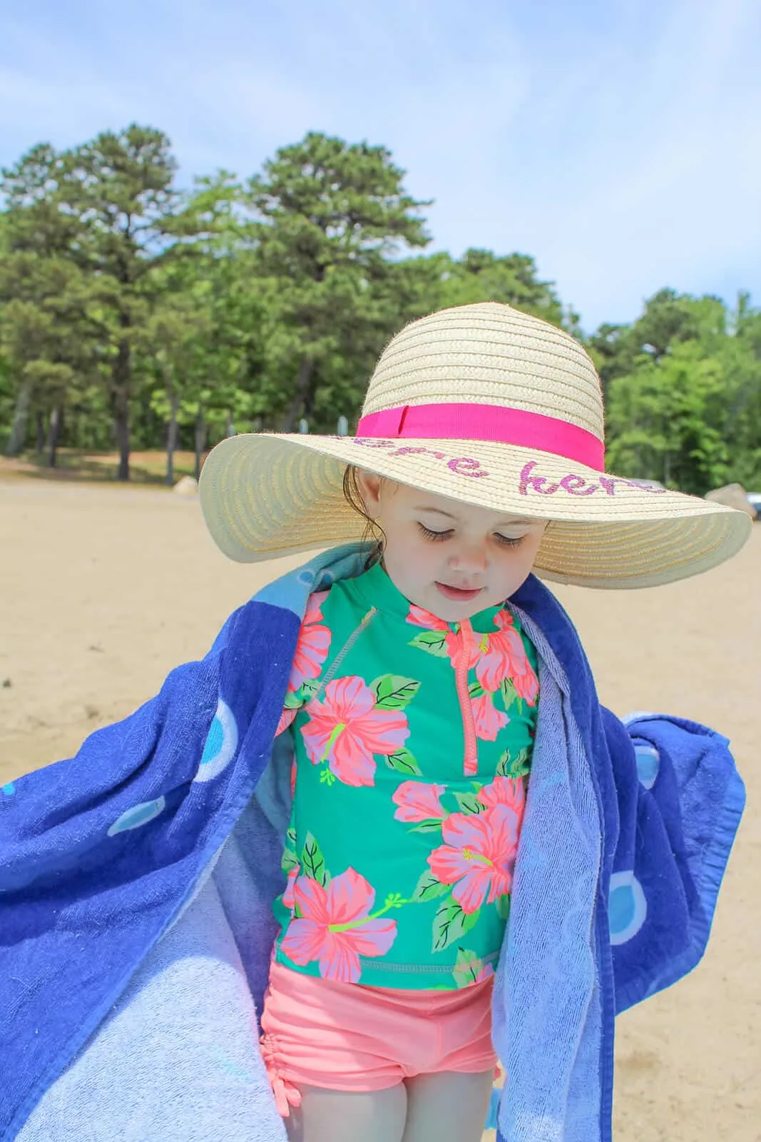 Baby wears large summer hat at beach.