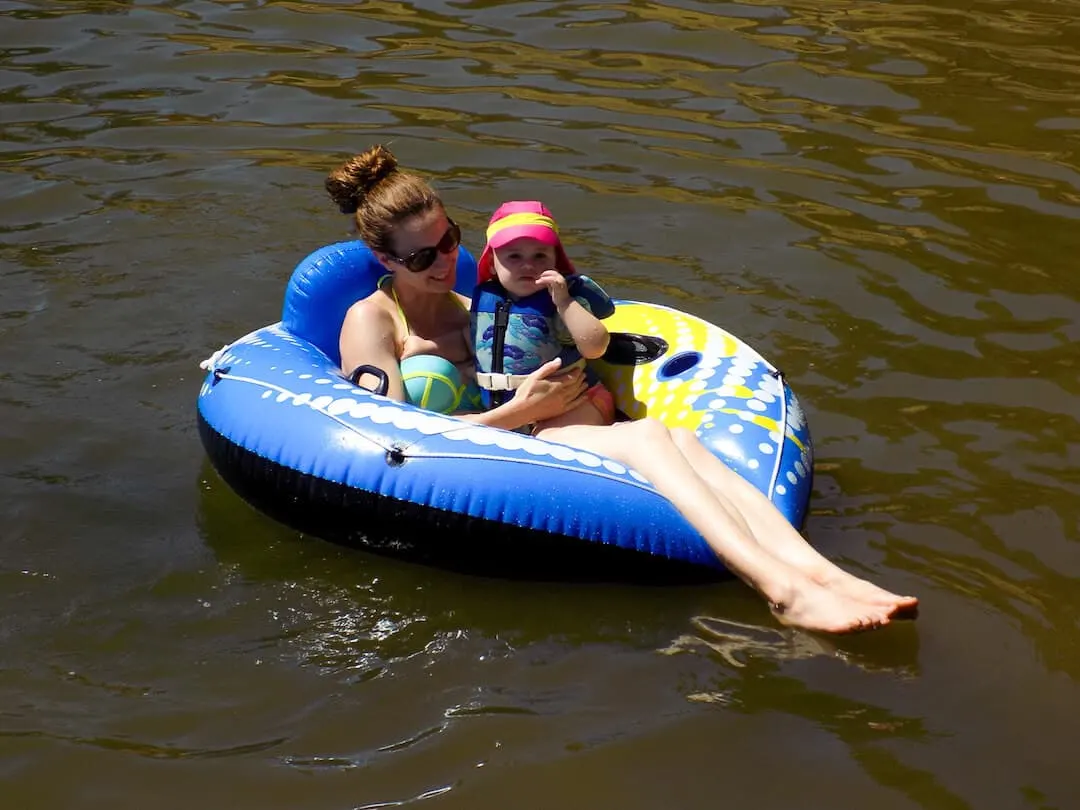 Mother and daughter float on tube in lake.