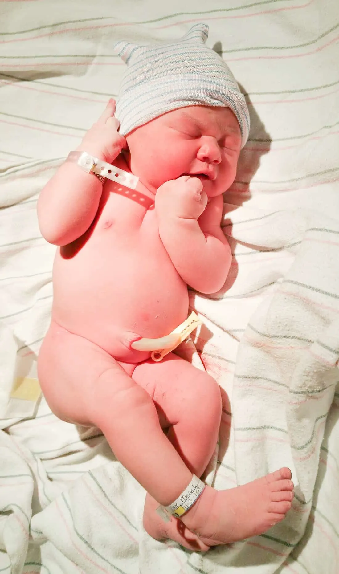 Newborn baby sleeps on hospital blanket.