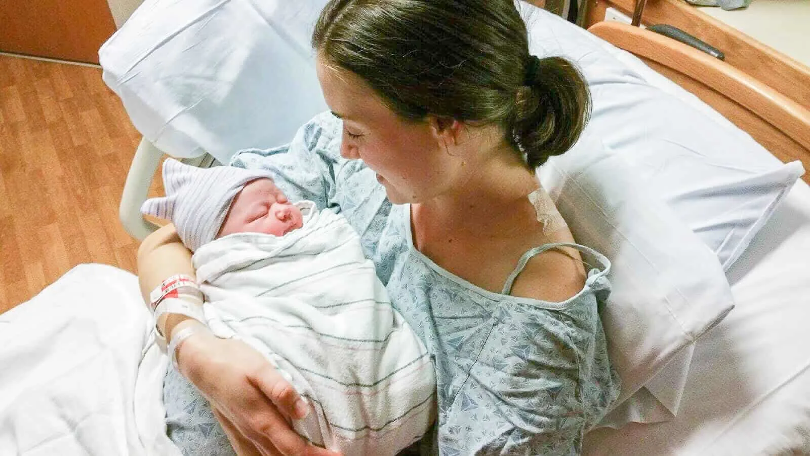 Mother holds newborn baby in hospital.