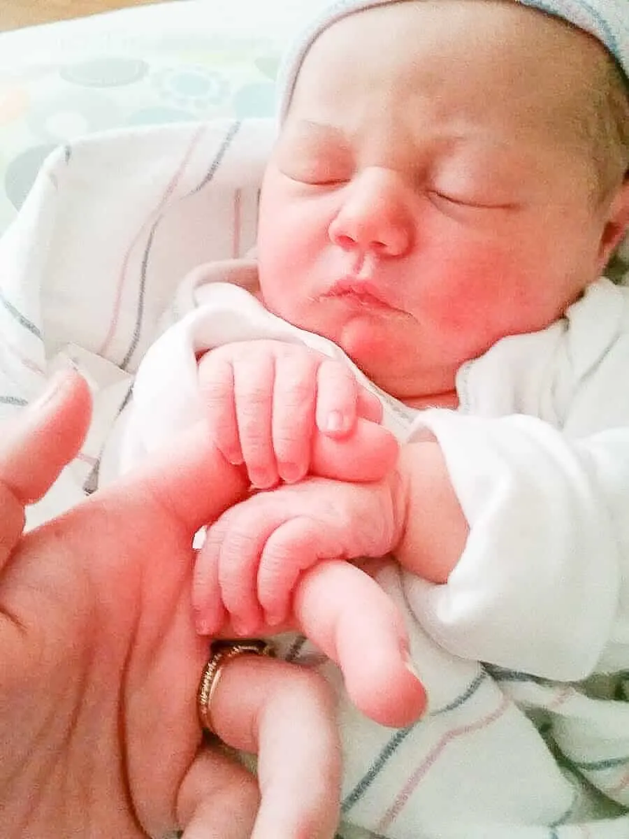 Newborn uses tiny hand to hold onto finger.