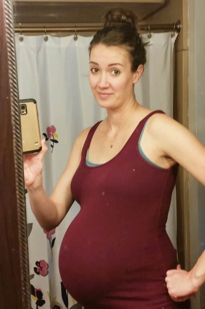 Pregnant woman take selfie in mirror.
