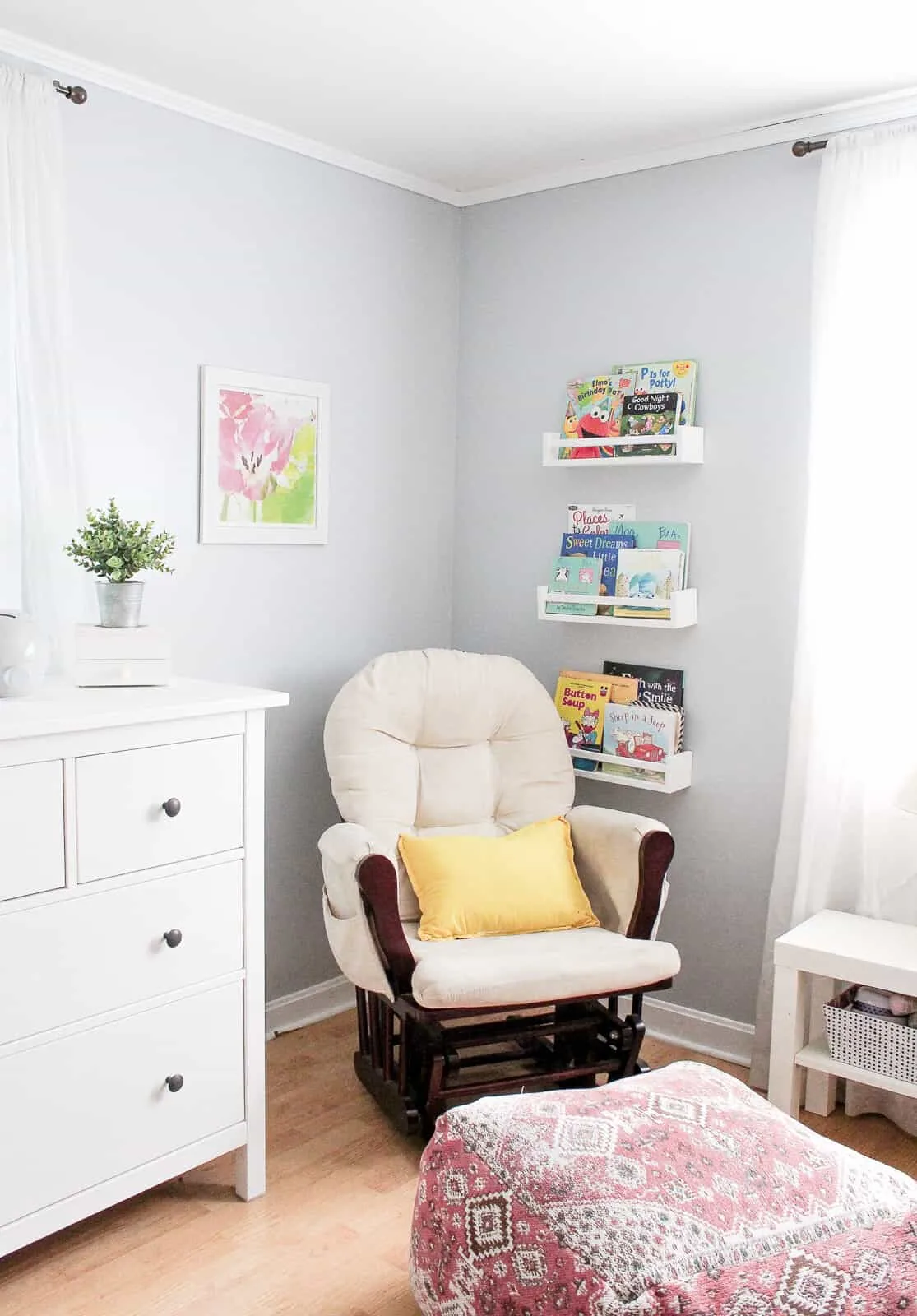 Rocking chair glider next to bookshelves in nursery.