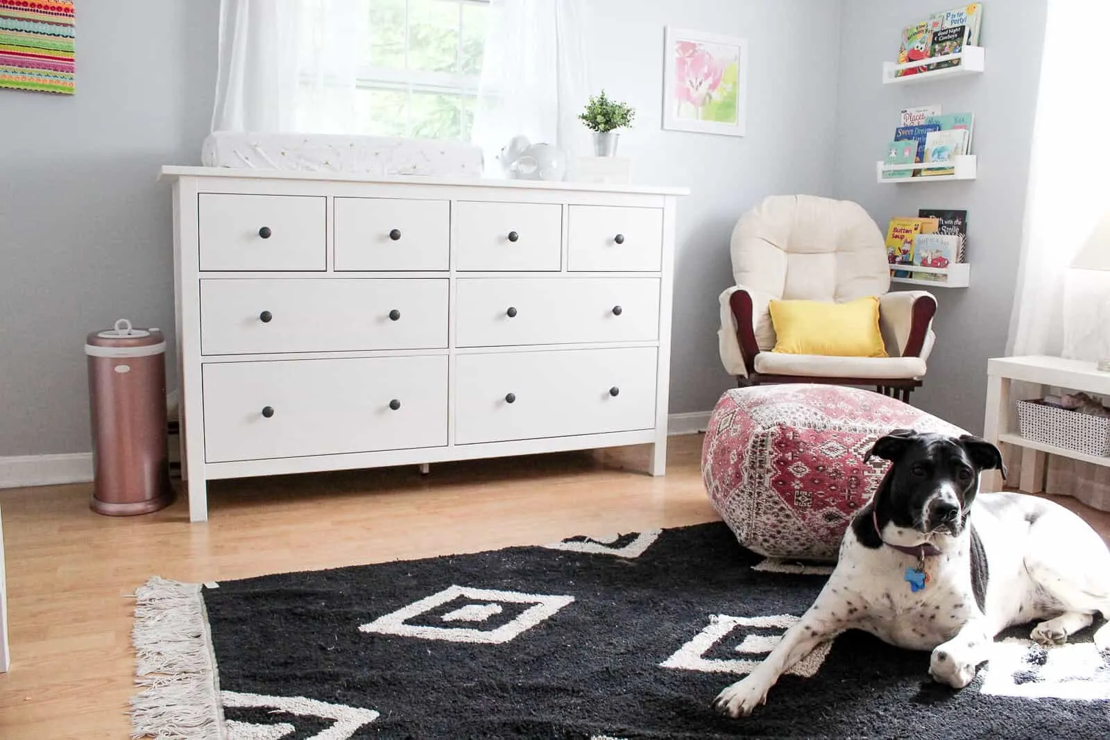 View of dresser and glider in modern baby girl bedroom.