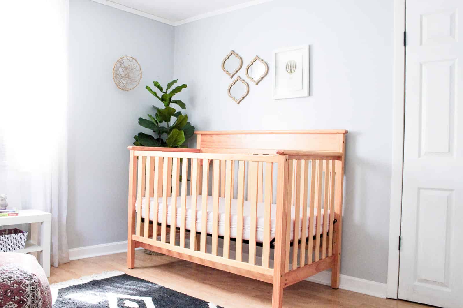 View of crib and wall decor in modern girl nursery.