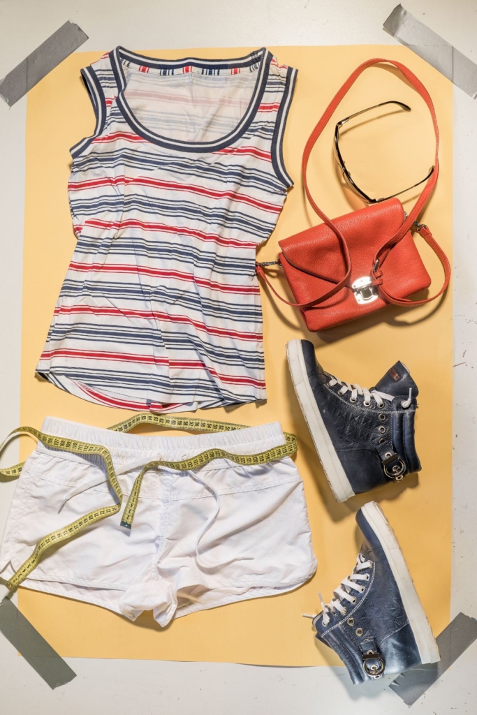 Flat lay outfit with with a stiped tank top, cream pants, and sneakers.