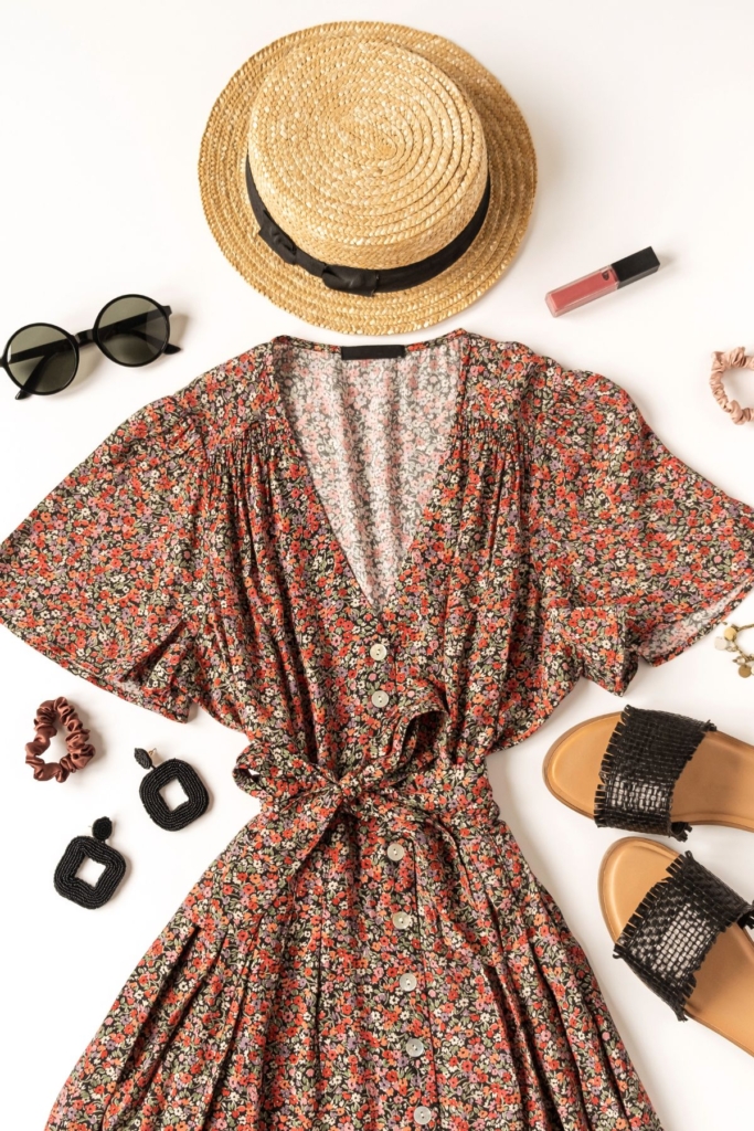 Flat lay outfit with with a brown floral summer dress and straw hat.