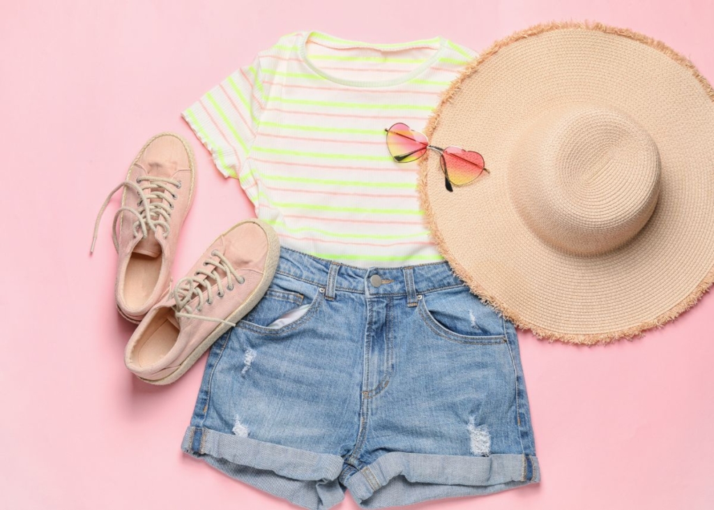Flat lay outfit with jean shorts and tan and cream striped shirt, casual shoes, and straw hat.