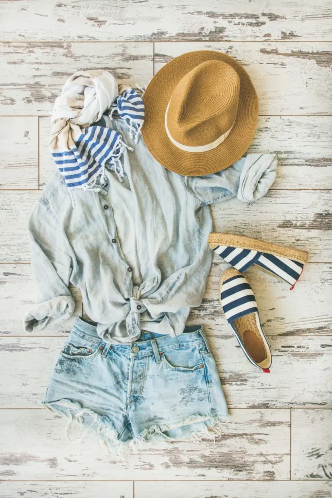 Flat lay outfit with with a soft jean blouse and jean shorts.