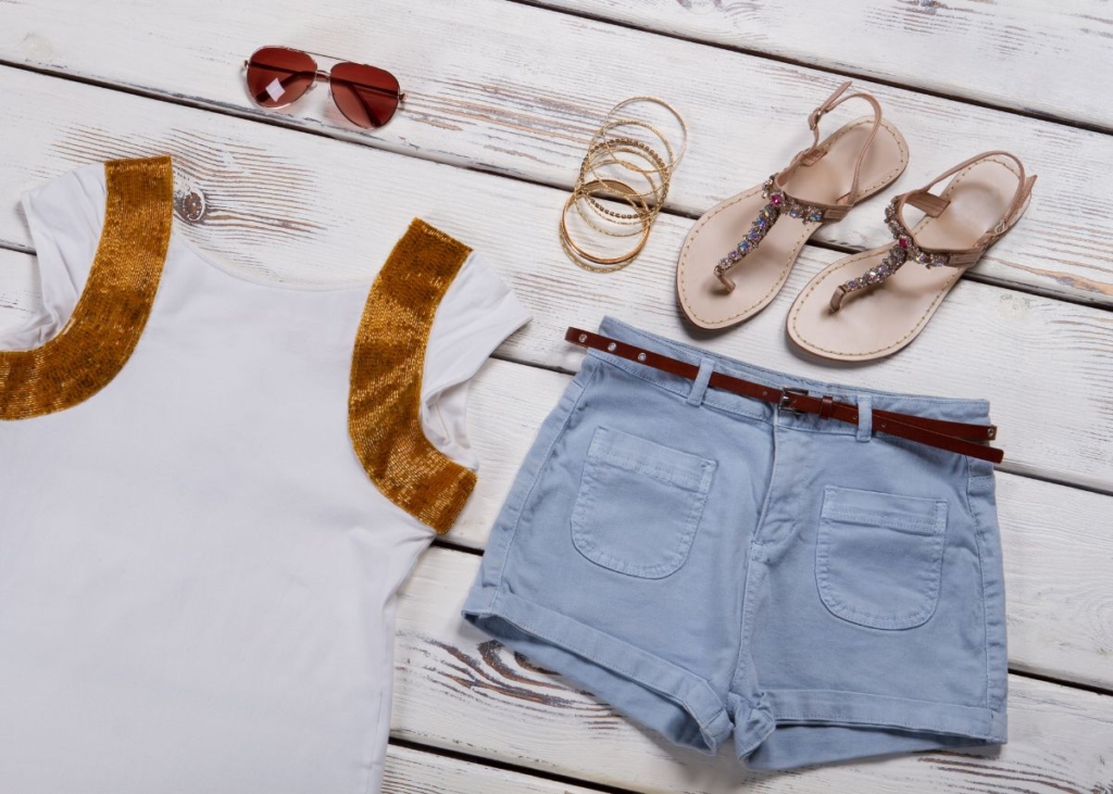 Flat lay outfit with with a white shirt, jean, shorts, and brown sandals.