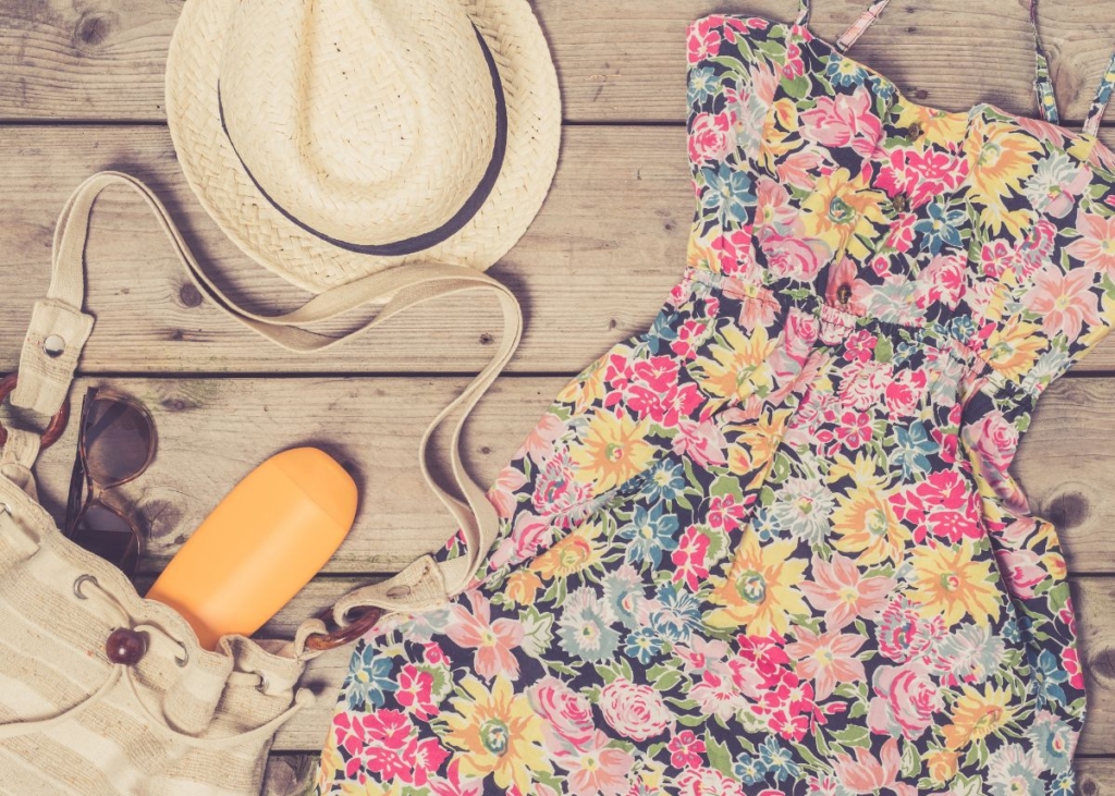 Flat lay outfit with floral summer dress and straw hat.