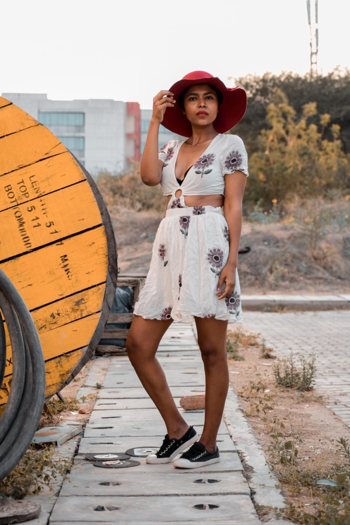 A woman on a beach walkway in a cropped top and flowy matching skirt.