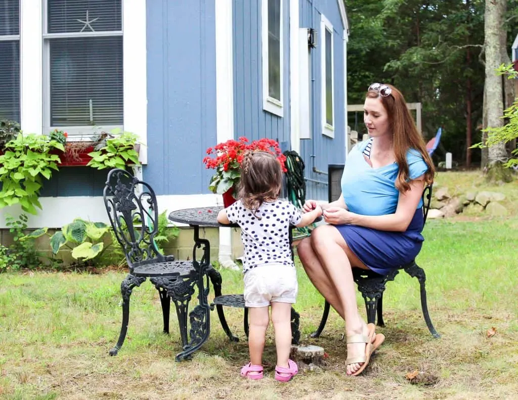 Mother sits with baby and toddler outdoors.