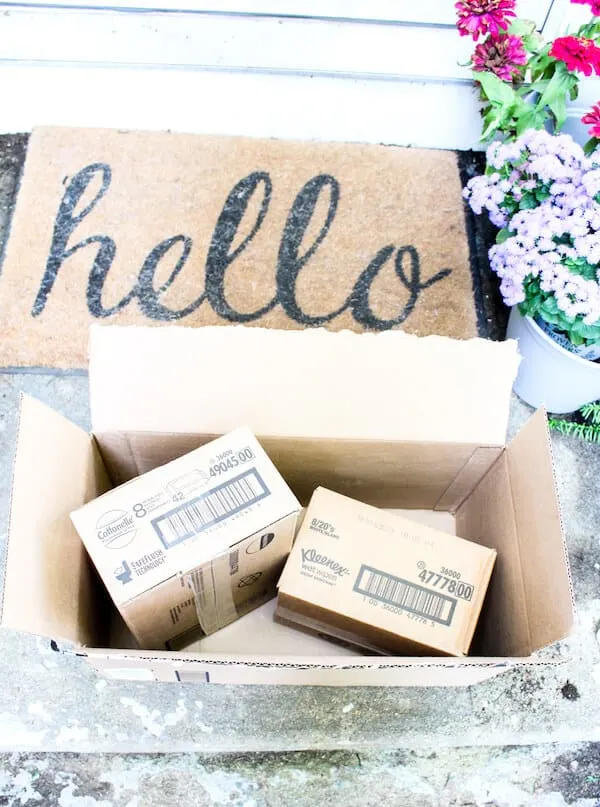 Amazon packages on doorstep next to \"Hello\" welcome mat.