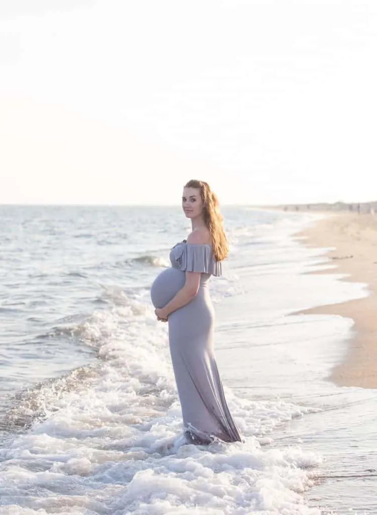 Woman poses for pregnancy photos on beach.
