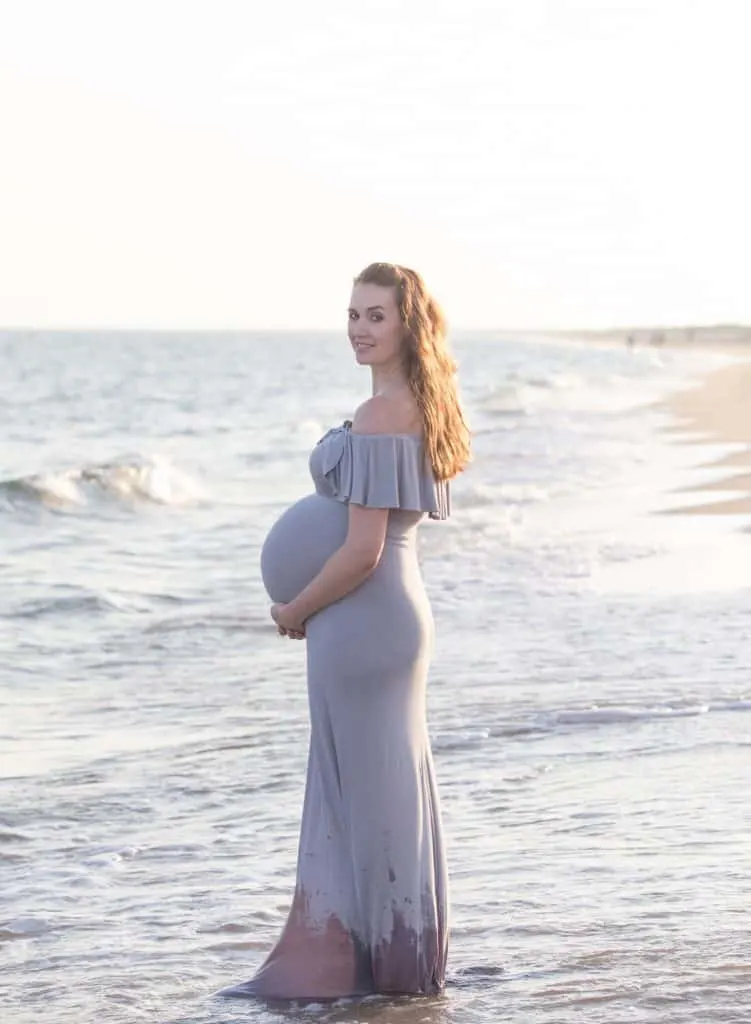 Woman in flowy dresses poses for pregnancy photos on Cape Cod beach.