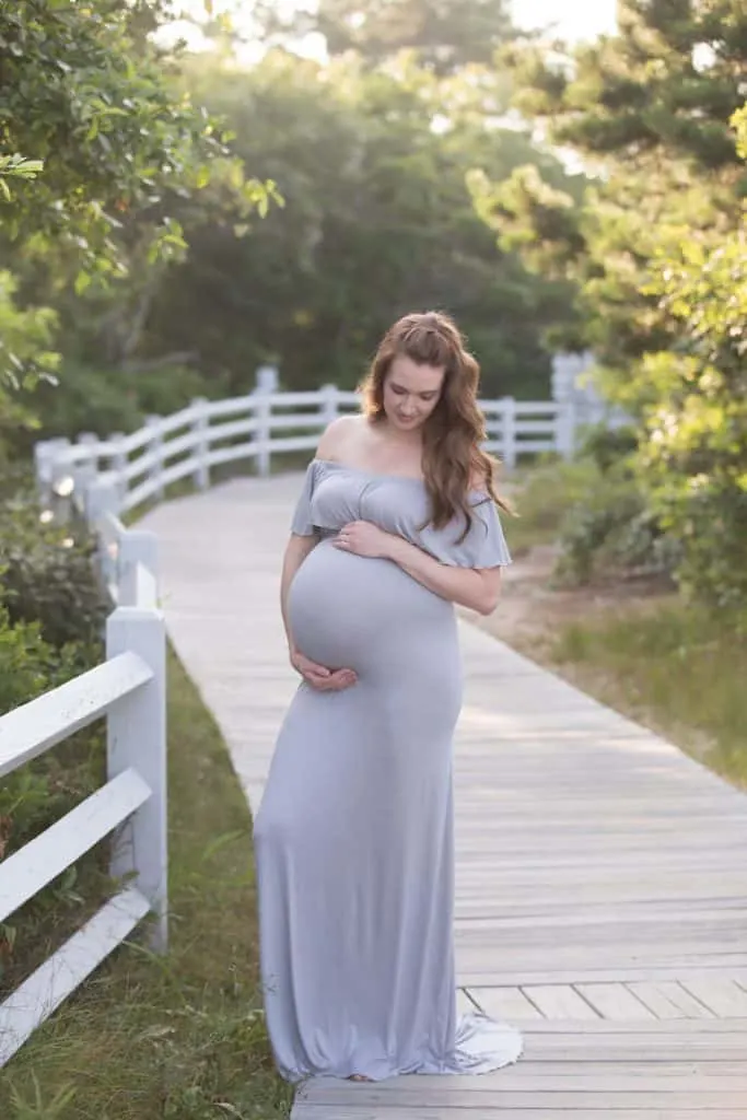 Woman poses on Cape Cod boardwalk for maternity photos.