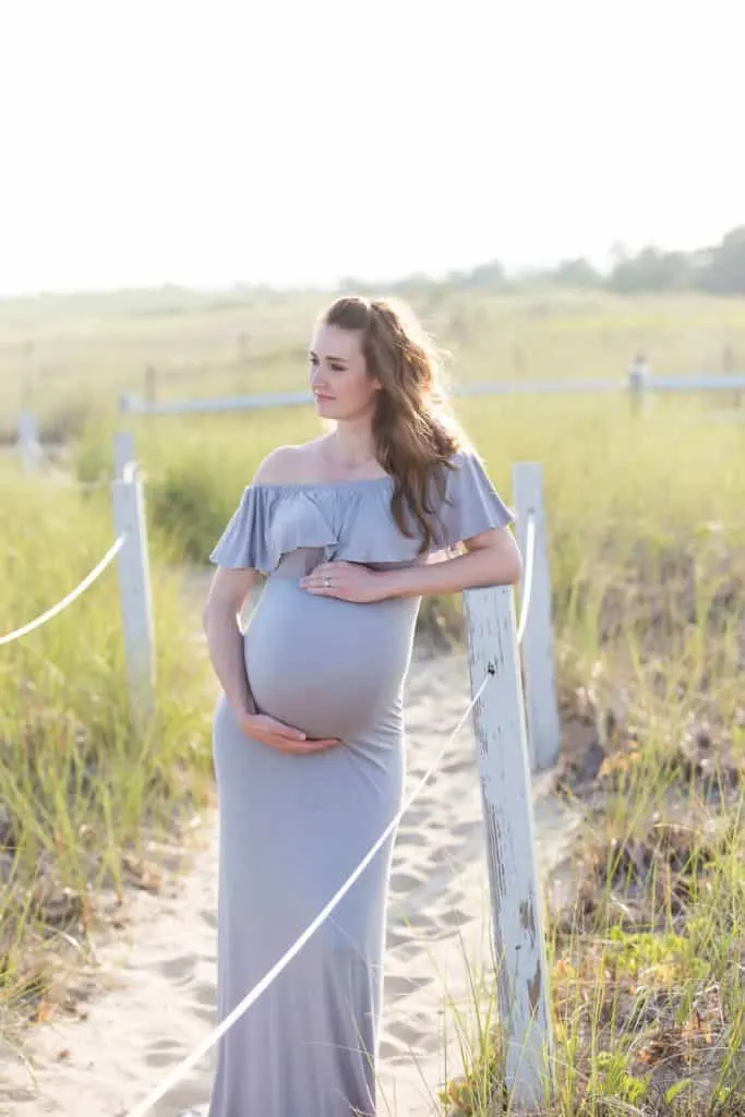 Woman takes maternity pictures on sandy path to Cape Cod beach.