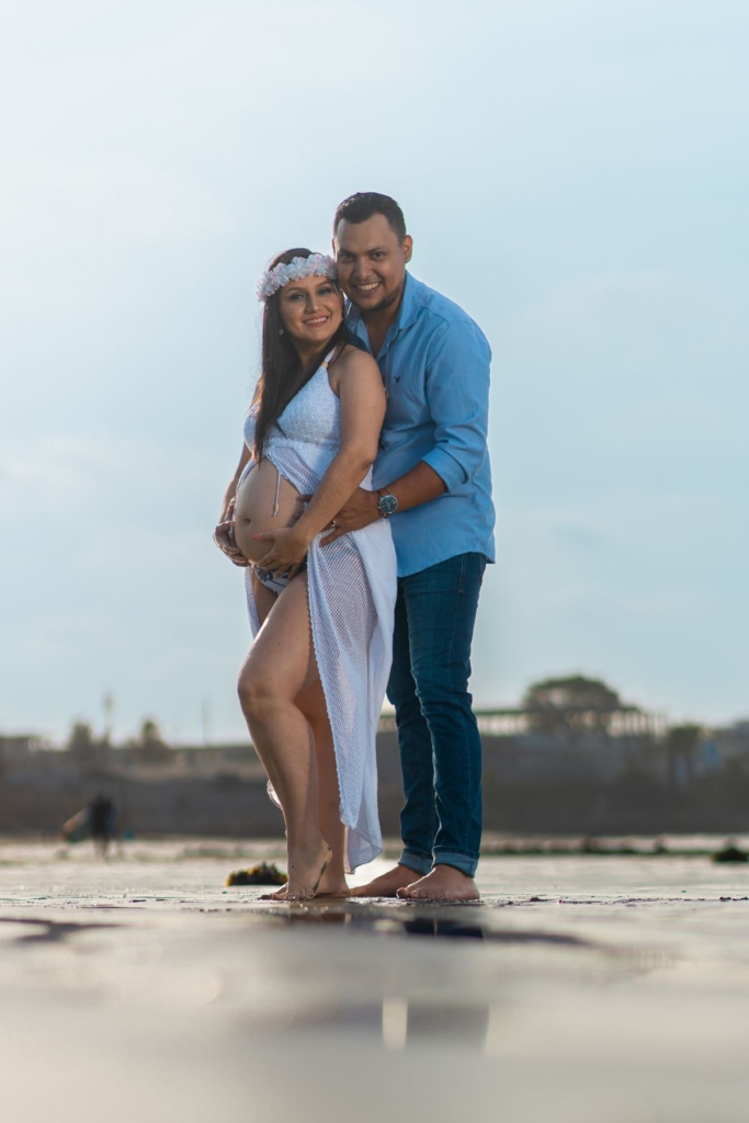 A couple embraces on the beach for maternity pictures.