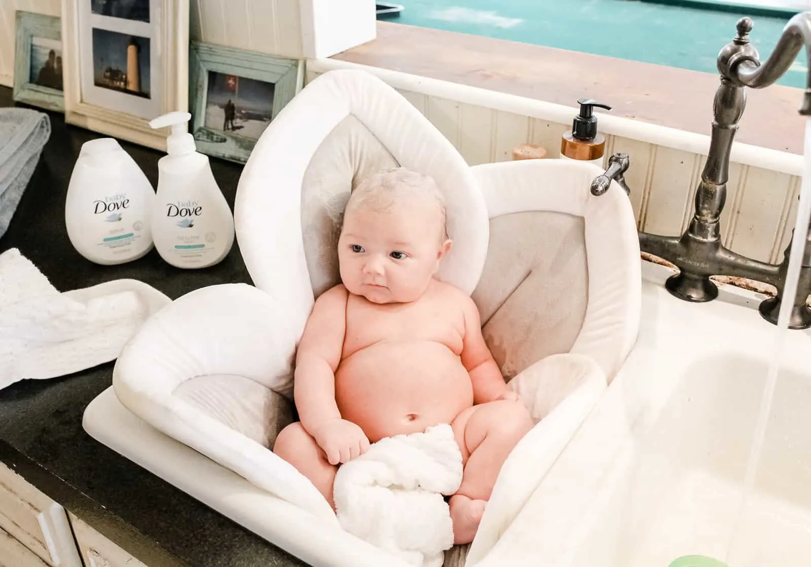Baby sits in bath on plush sink liner.